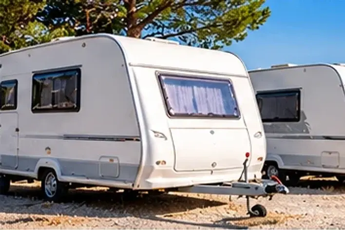 Caravanes alignées sur une aire de stationnement extérieure, sous les pins